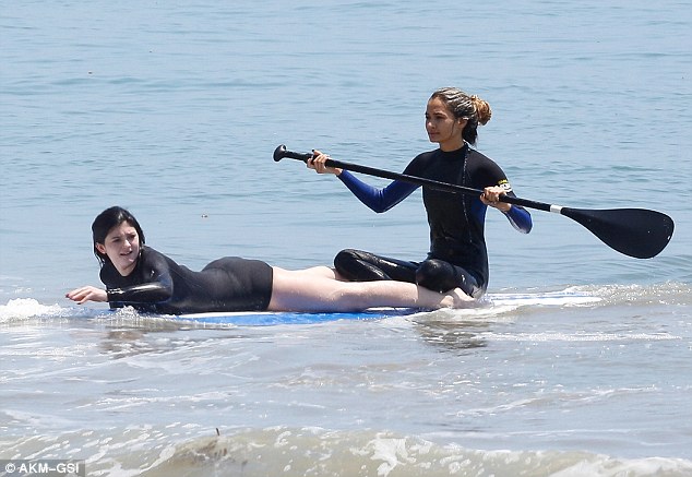 Different look: On Thursday Kylie enjoyed a day at the beach with friends and family, jumping into a wetsuit and going paddle boarding